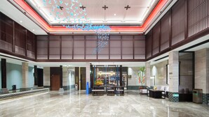 A spacious lobby with a high ceiling, a reception desk, and a seating area.
