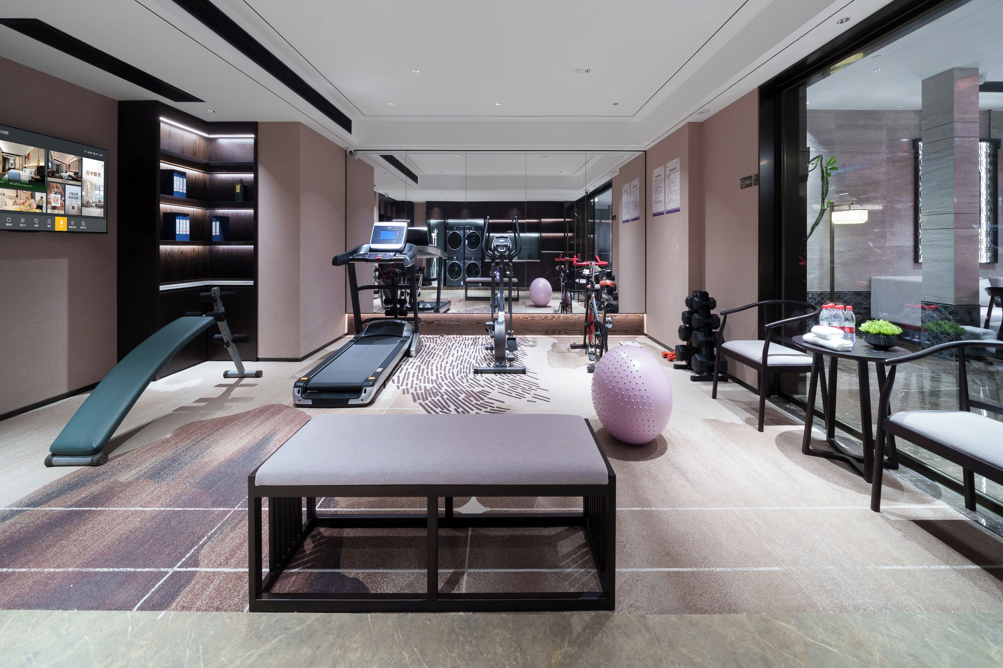 A fitness center with exercise equipment, a treadmill, and a seating area.