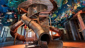 A large, industrial-style structure with multiple pipes and a mesh enclosure, set against a backdrop of colorful marine life decorations. - Big Cedar | Rustic Retreat | Pools, Lake & Adventure (Ridgedale)