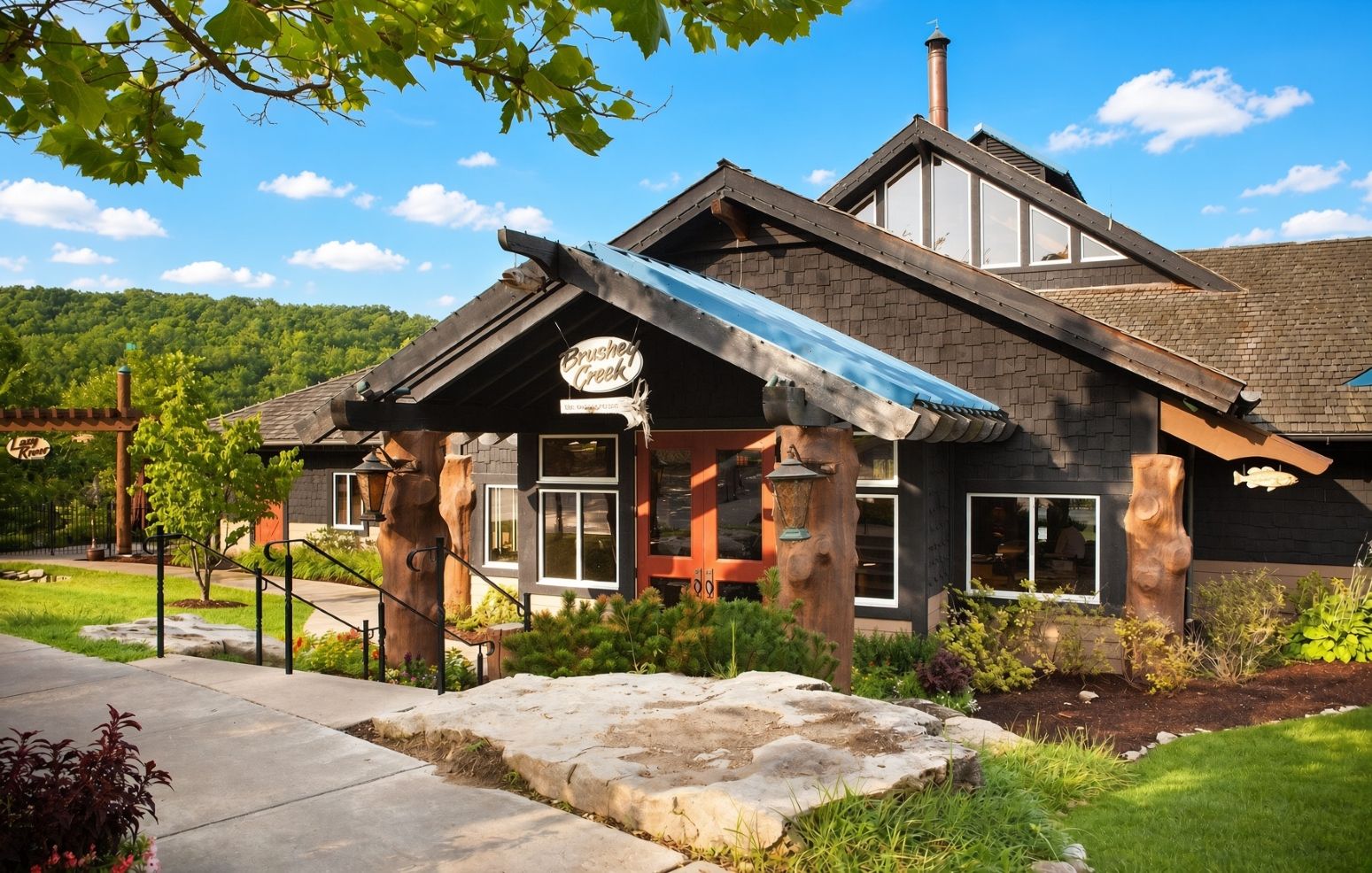 Un chalet doté d’une façade en pierre, de grandes fenêtres et d’un porche abrité.