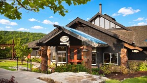 A lodge with a stone facade, large windows, and a covered porch. - Big Cedar | Rustic Retreat | Pools, Lake & Adventure (Ridgedale)