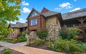 A log cabin-style building with a stone foundation, a large window, and a stone chimney. - Big Cedar | Rustic Retreat | Pools, Lake & Adventure (Ridgedale)