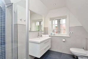 Un baño moderno con ducha, lavamanos, inodoro y ventana.