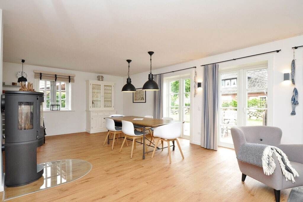 Ein großzügiger Wohnbereich mit Holzboden, einem Esstisch mit Stühlen, einer Couch und einem Kamin.