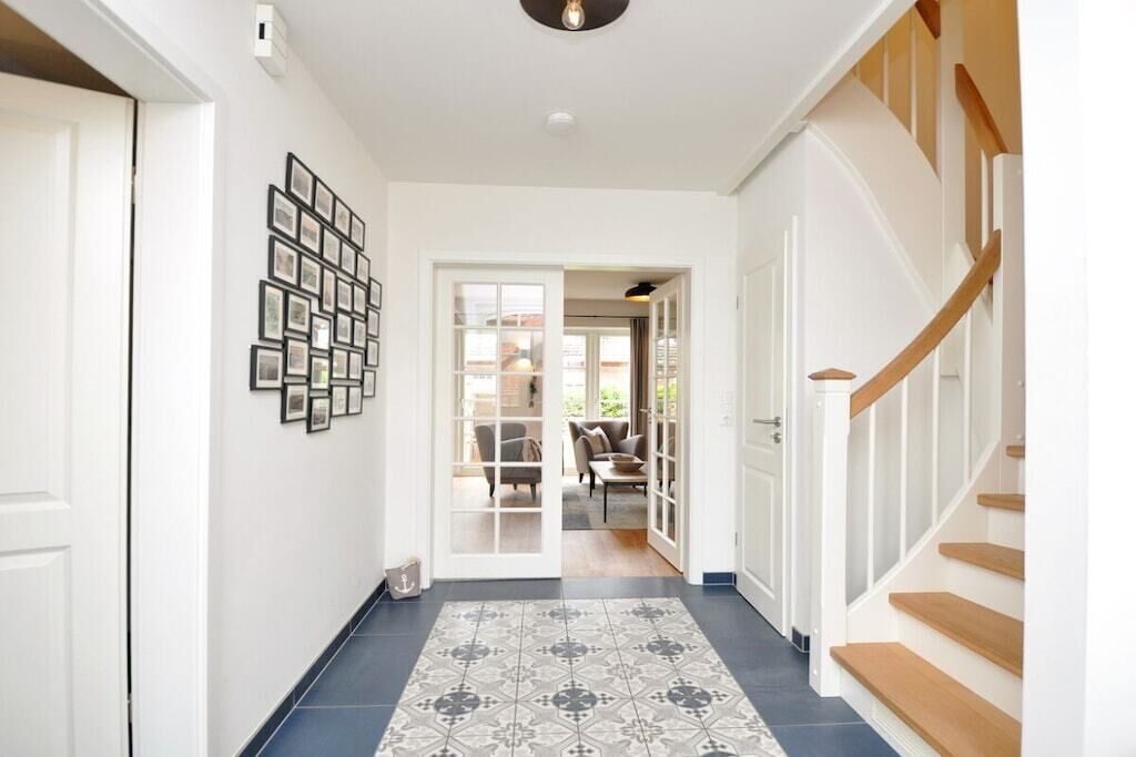 Ein Korridor mit einem gemusterten Boden, einer Treppe und einer Tür zu einem Zimmer mit Blick.