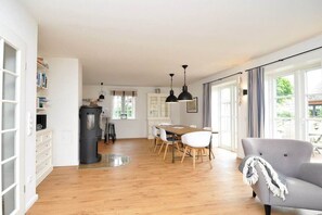 A spacious living area with a dining table, a grey armchair, and a bookshelf. - Holiday home with 1 bedroom (St.Peter-Ording)