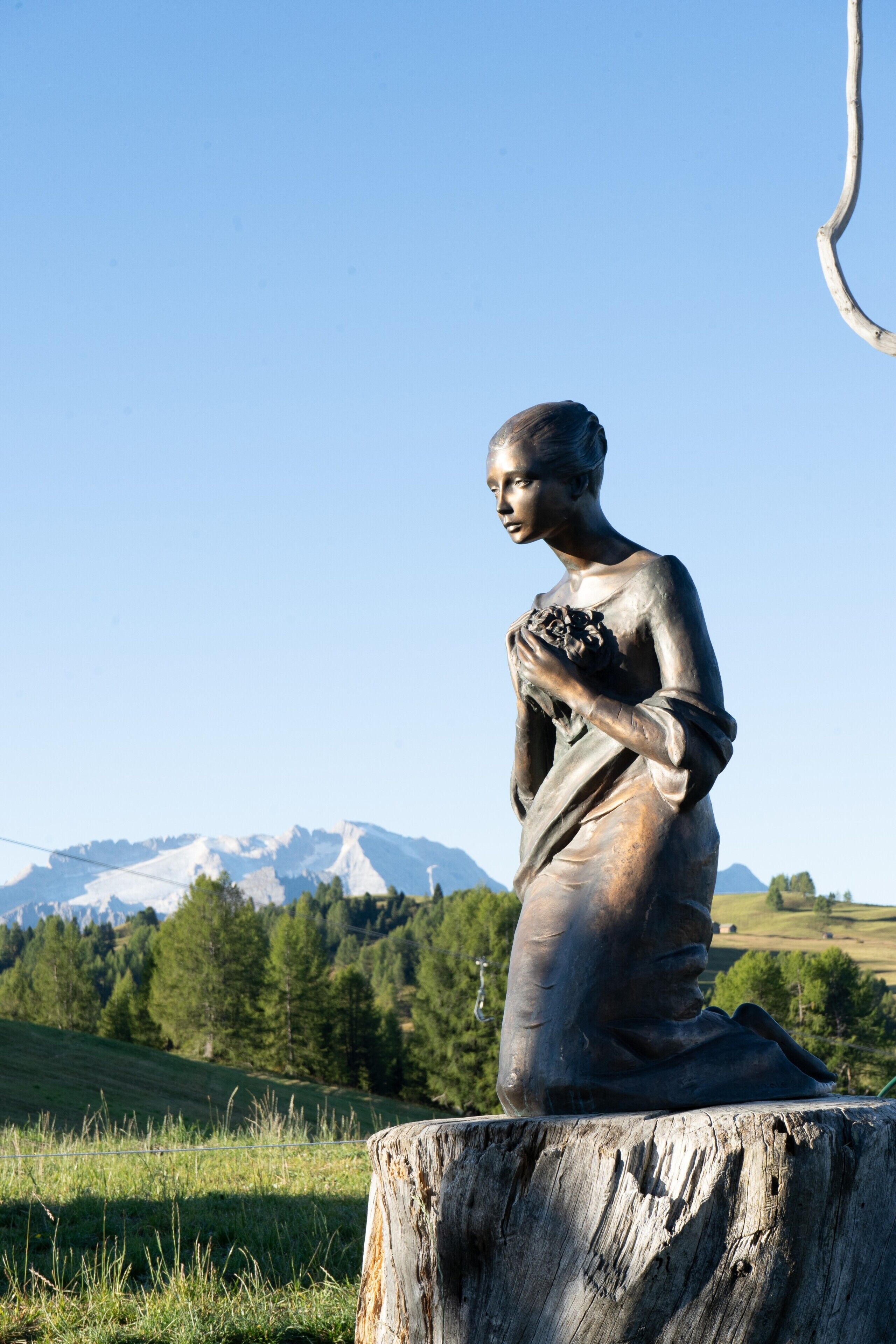 Una estatua de una mujer en un campo, con una montaña al fondo.