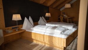 Una habitación con una cama de madera, dos mesitas de noche, un escritorio y una silla.