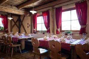 A restaurant with wooden tables and chairs, red curtains, and hanging lights. - Room 12 with Mountain View (Badia)