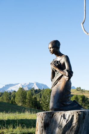A statue of a woman in a field with a mountain in the background.