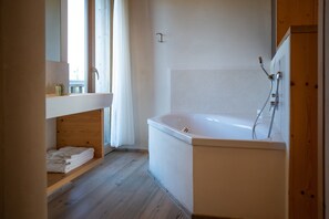 A modern bathroom with a bathtub, a sink, and a wooden shelf. - Superior Family Room 7 with Mountain View (Badia)