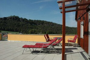 Eine Dachterrasse mit roten Liegestühlen und einer Holz-Pergola.