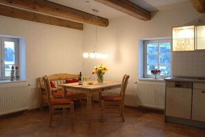 Un coin repas avec une table et des chaises en bois, un vase de fleurs et une fenêtre donnant sur un beau paysage.