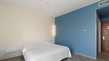 Ein Schlafzimmer mit einem Einzelbett, einer blauen Akzentwand und einer Holztür.