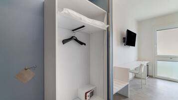 Une chambre moderne avec une armoire blanche, un bureau et un téléviseur.