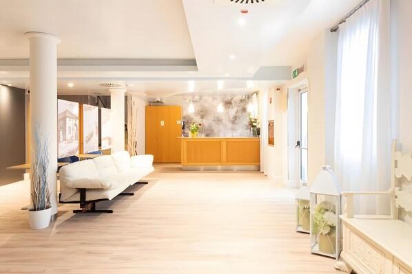 A hotel lobby with a reception desk, seating area, and a decorative wall.