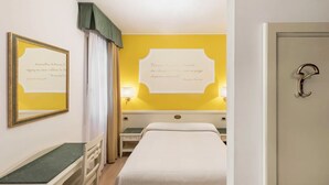 Una camera d'albergo con un letto, un comodino, una lampada e una porta.
