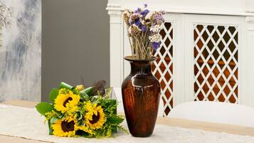 A dining table with a vase of sunflowers and a decorative arrangement on a mantelpiece.