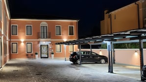 Un edificio con un'area di parcheggio coperta e un'auto parcheggiata all'interno.