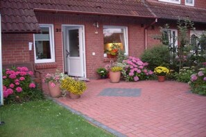 Ein Haus aus Ziegeln mit rotem Ziegeldach, einer weißen Tür und einem gepflasterten Auffahrt.