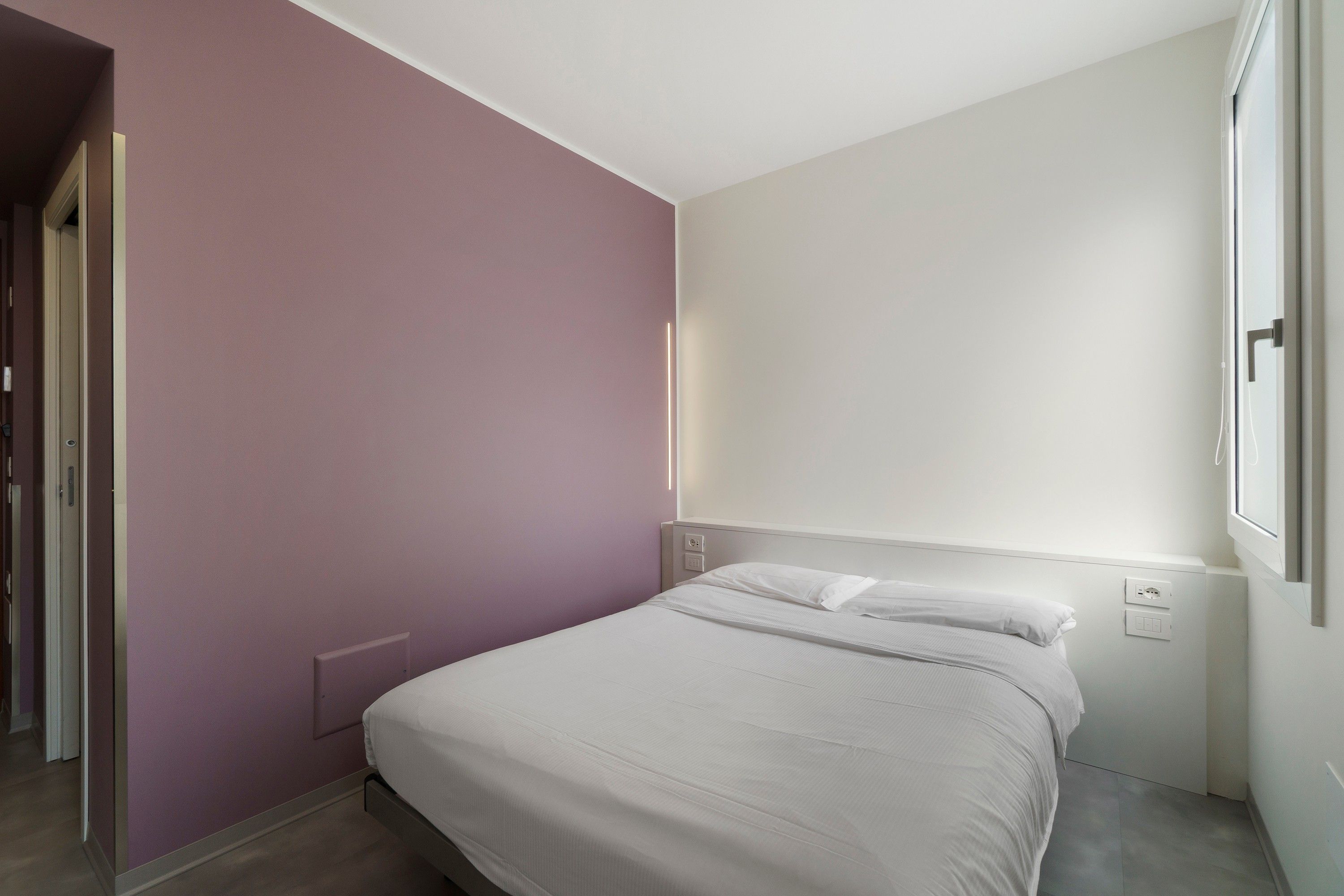 Une chambre à coucher avec un lit, une porte et une fenêtre.