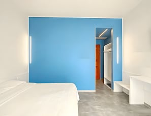 A modern hotel room with a large bed, a blue accent wall, and a walk-in closet. - Room 'Camera Matrimoniale Standard' with Wi-Fi and Air Conditioning (Venice)