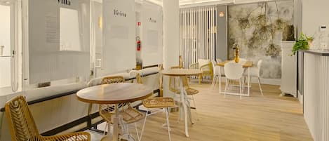 Un intérieur moderne avec des tables rondes et des chaises en osier, des murs blancs et un plancher en bois.