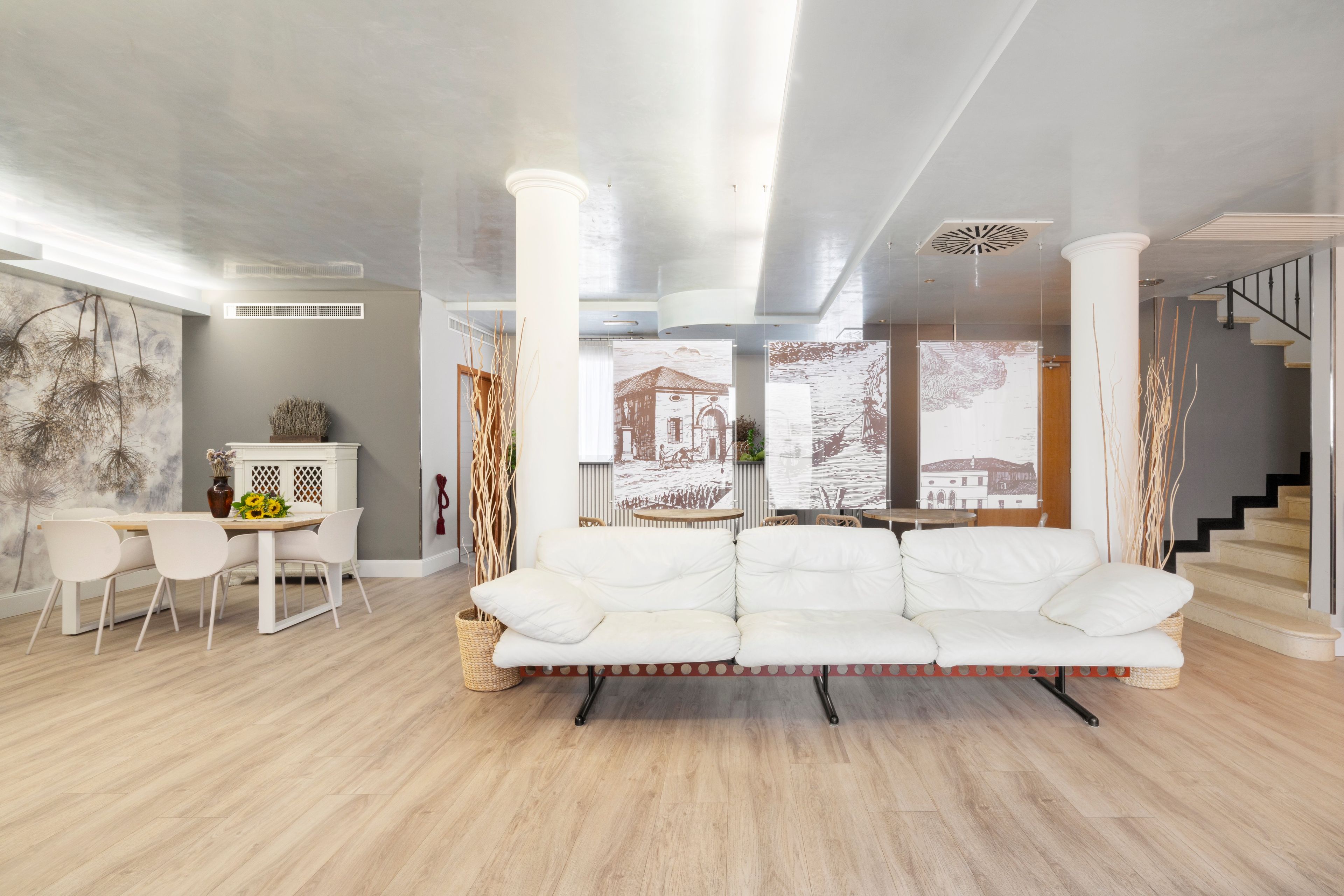 Ein modernes Wohnzimmer mit einem weißen Sofa, einem Esstisch mit Stühlen und einer Treppe.