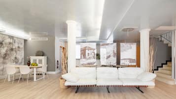 Ein modernes Wohnzimmer mit einem weißen Sofa, einem Esstisch mit Stühlen und einer Treppe.