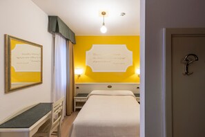 Een hotelkamer met een bed, een bureau, een stoel, een nachtkastje en een muur met een citaat.