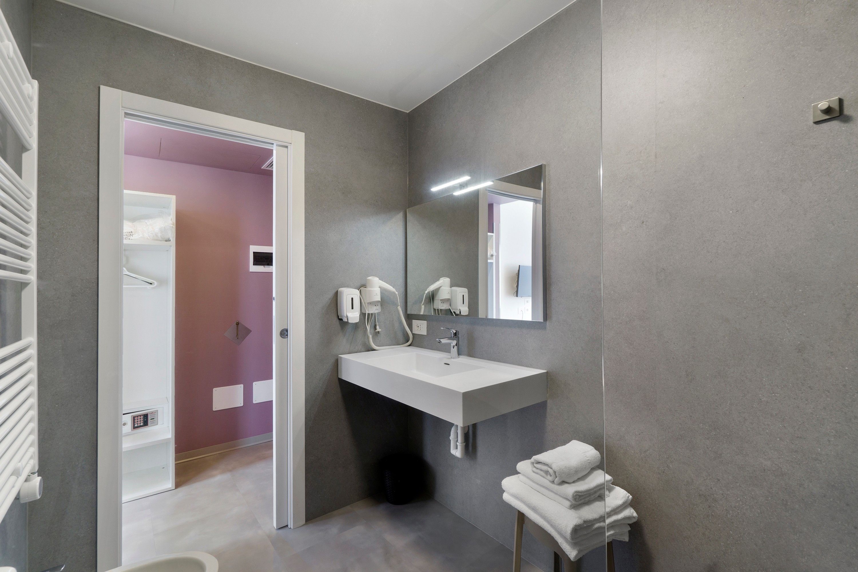 Un baño moderno con un lavamanos blanco, un espejo y un perchero para toallas.
