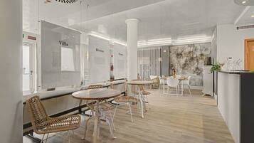 Un intérieur moderne avec un espace bar, des sièges avec des fauteuils en osier et un mur décoratif agrémenté de plantes.