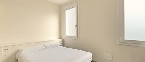 A bedroom with a single bed, a window, and a wall socket.