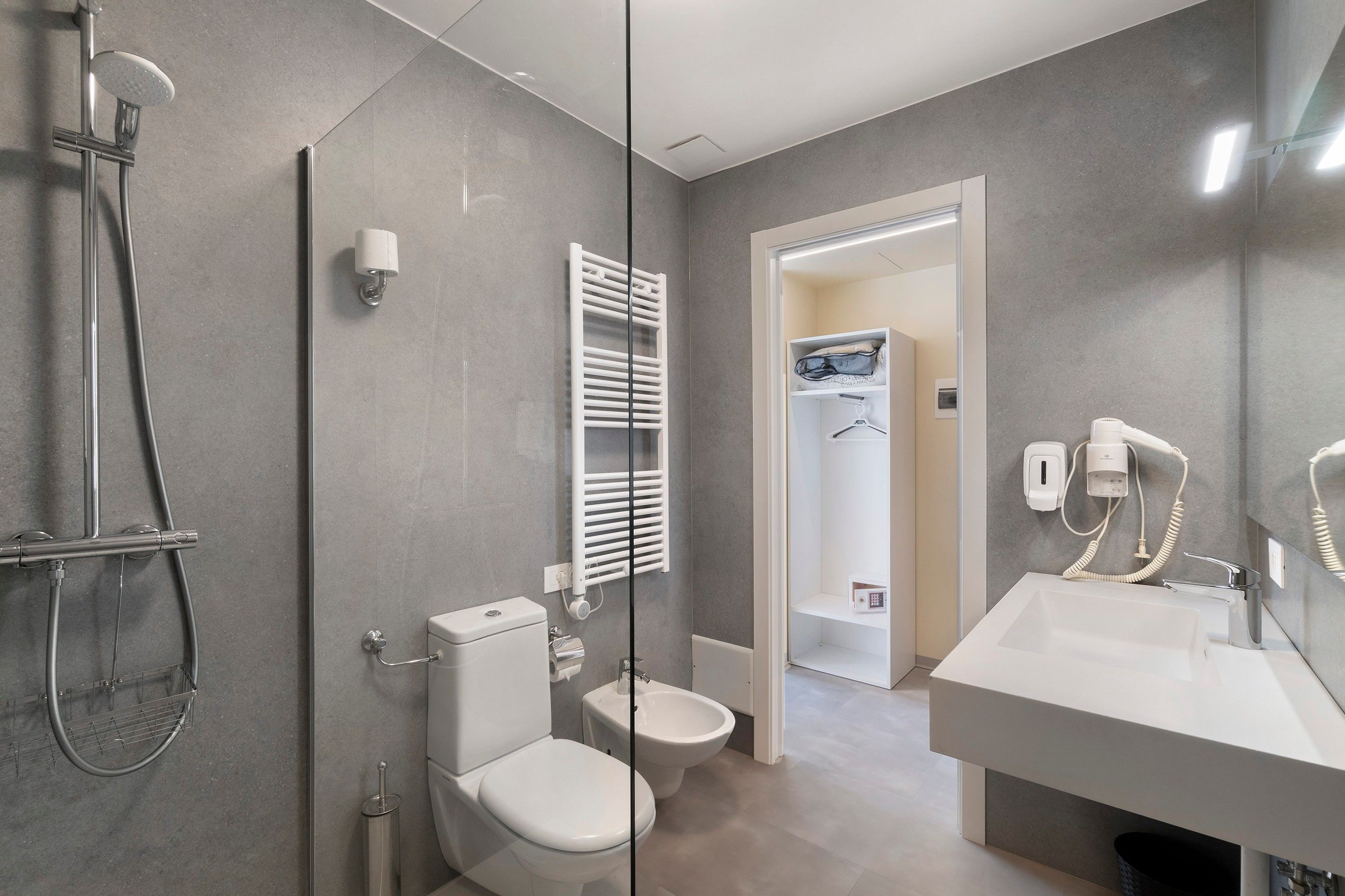 Une salle de bain moderne dotée d’une douche à parois de verre, de toilettes, d’un bidet et d’un meuble-lavabo avec un évier et un miroir.