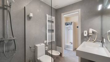 Une salle de bain moderne dotée d’une douche à parois de verre, de toilettes, d’un bidet et d’un meuble-lavabo avec un évier et un miroir.