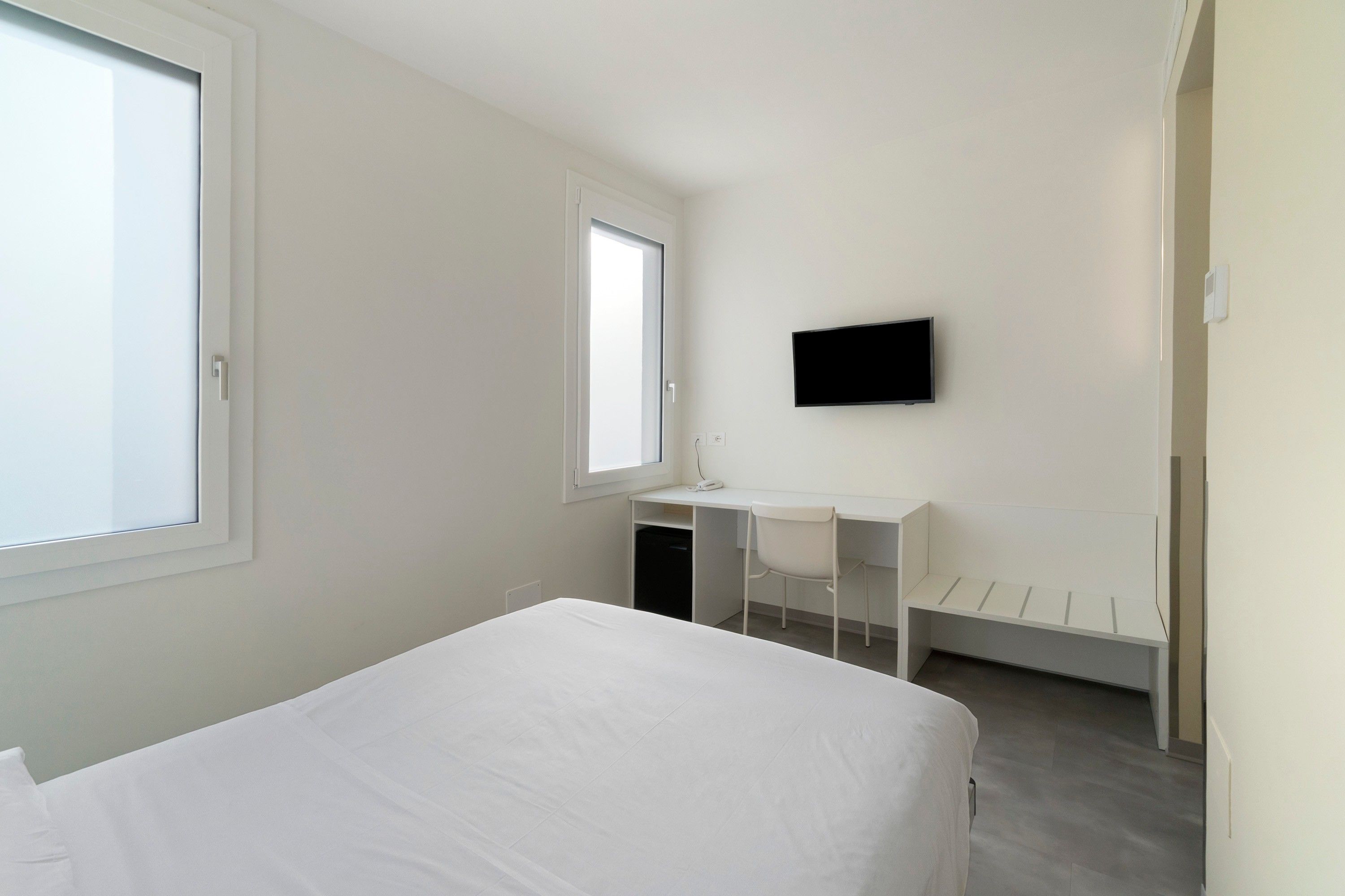 Ein Schlafzimmer mit einem Bett, einem Schreibtisch und einem Fernseher.