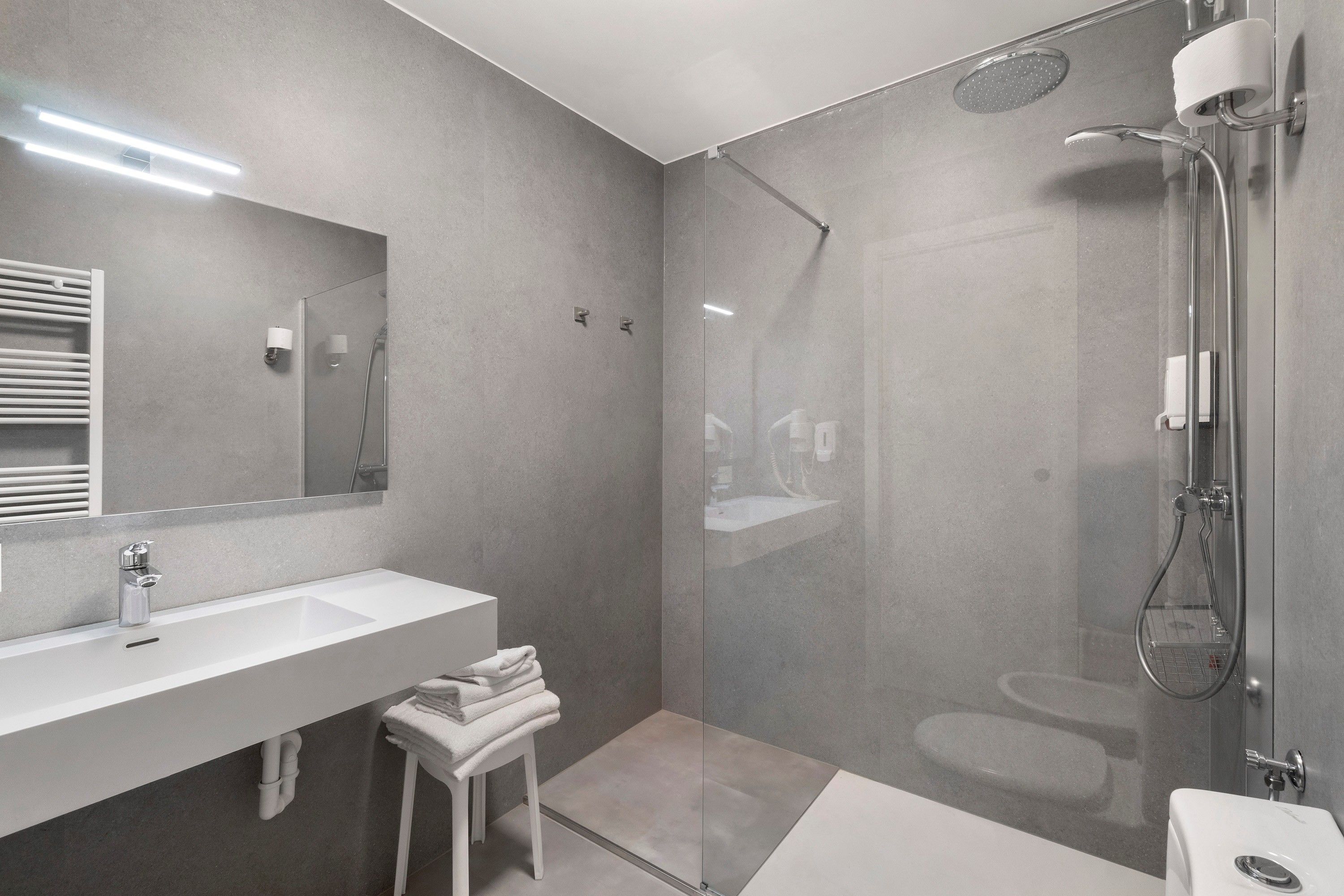 A modern bathroom with a glass-enclosed shower, a white sink, and a mirror.