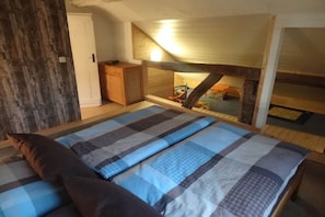 A bedroom with a bed, a wooden wardrobe, and a sloped ceiling with a skylight. - Holiday home in Monschau with swimming pool (Monschau)
