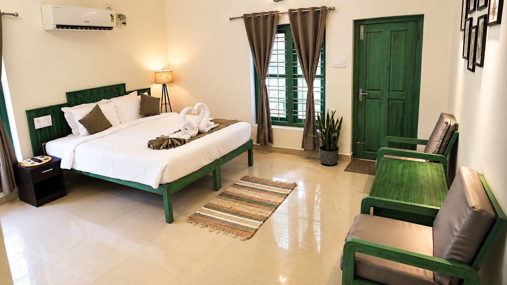 Habitación de hotel con cama, mesita de noche, lámpara, cortinas, una puerta verde y una silla verde.