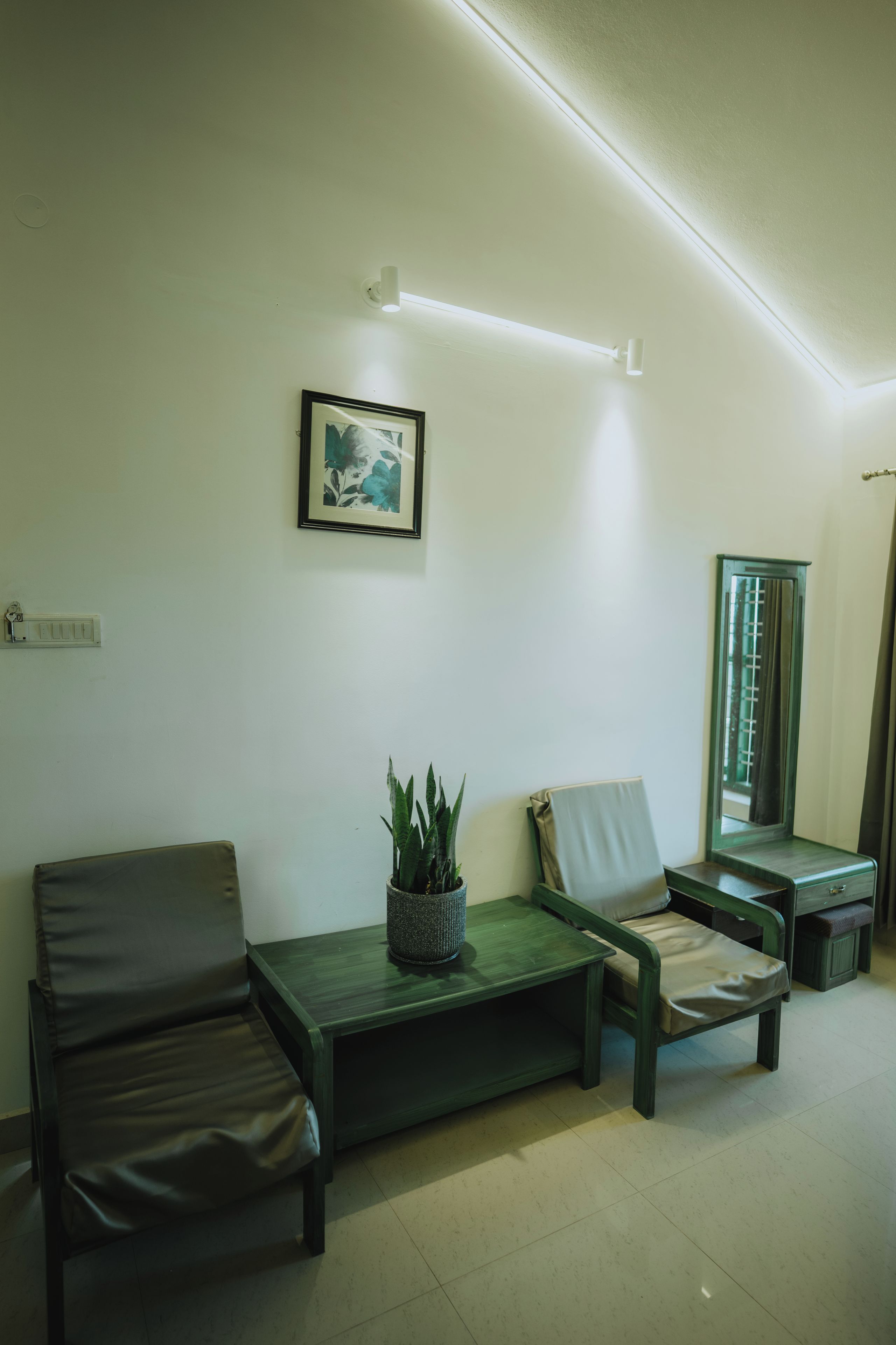 A room with a sofa, a small table with a plant, a framed picture on the wall, and a mirror.