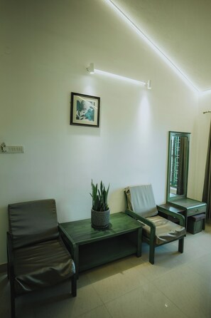 Una habitación con un sofá, una mesita con una planta, un cuadro en la pared y un espejo.