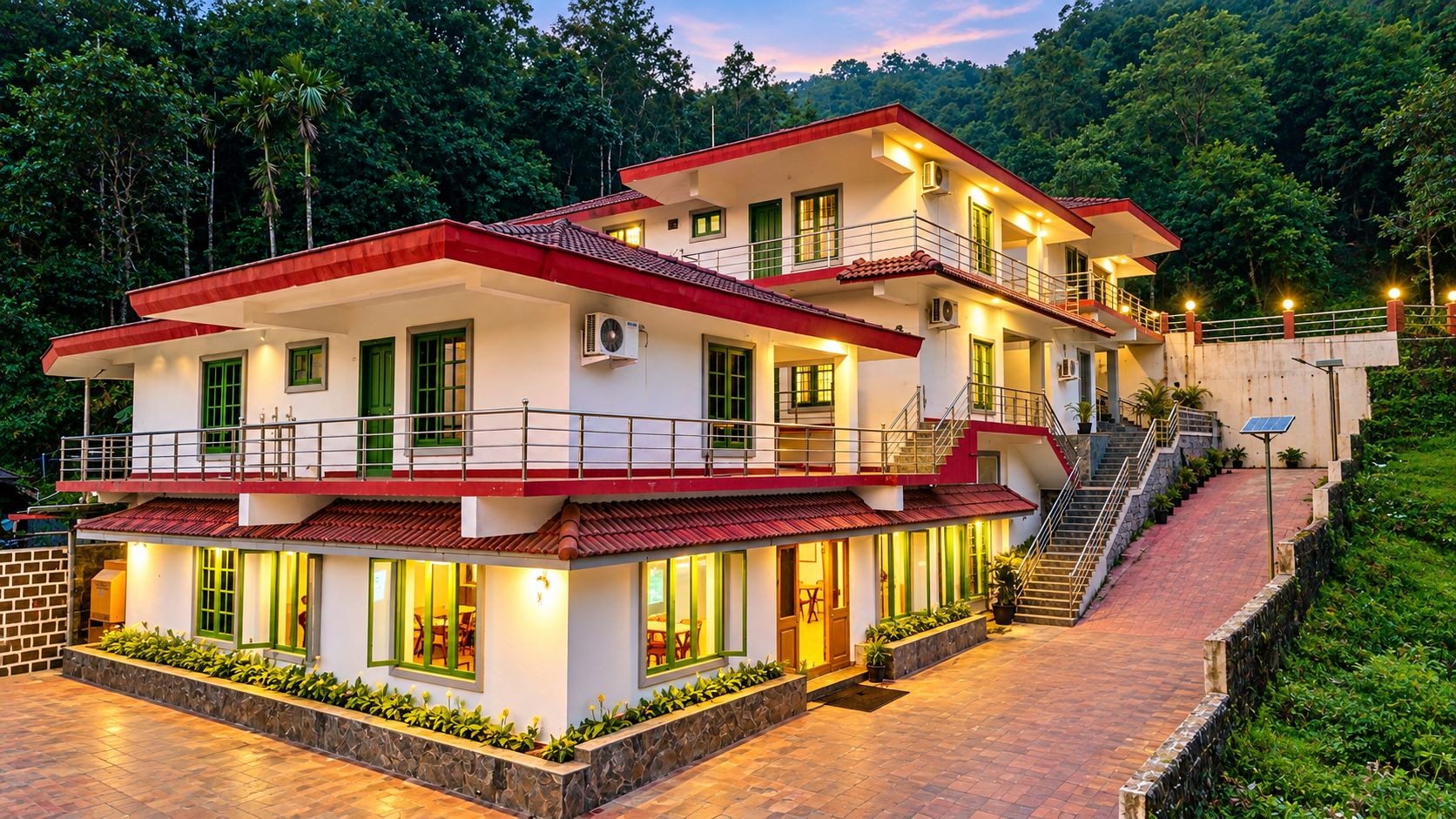 Un edificio de dos pisos con techo rojo, varios balcones y un paseo pavimentado.