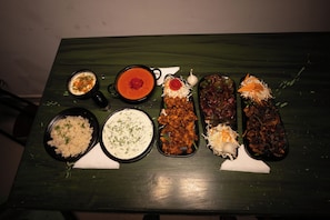 Una mesa con diversos platos, como arroz, una sopa cremosa y varios guisos de carne, sobre un mantel verde.