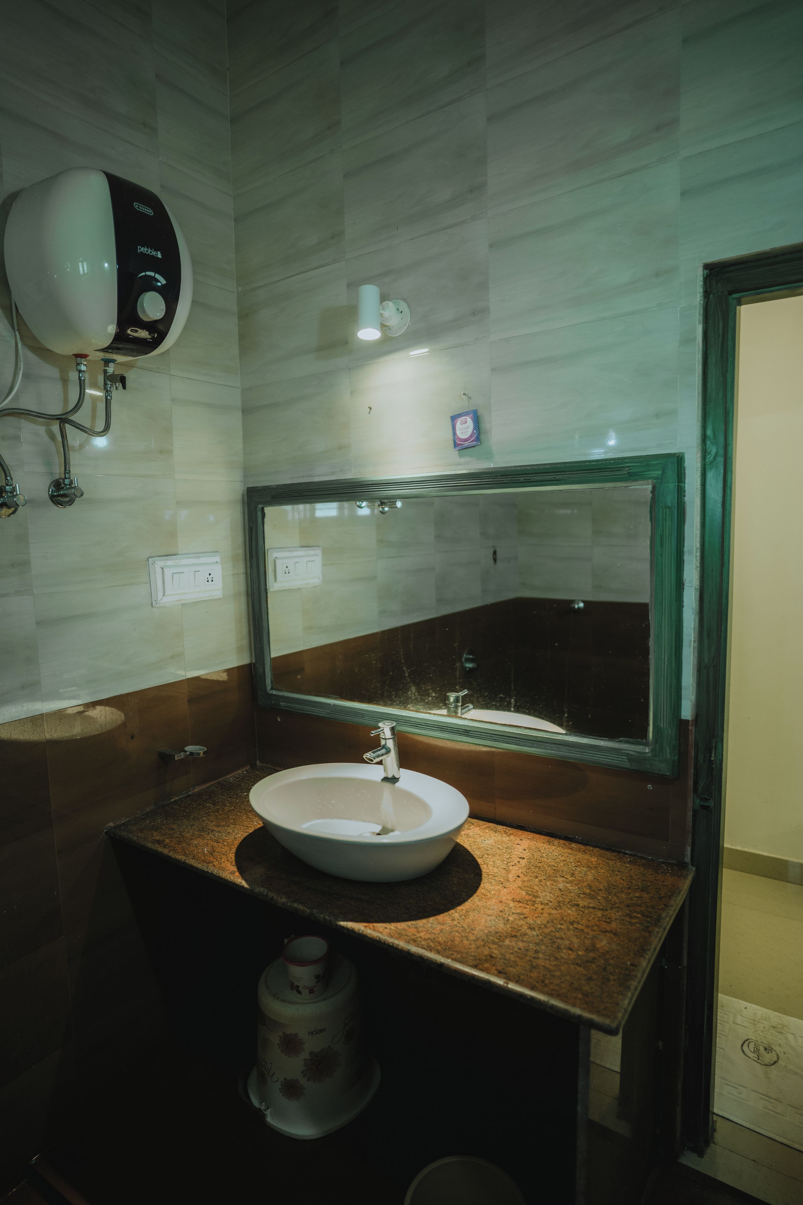 Casa de banho com lavatório branco, espelho e dispensador de sabonete fixado na parede.