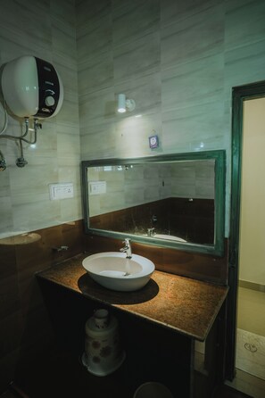 Un ba ño con un lavamanos blanco, un espejo y un dispensador de jabón en la pared.
