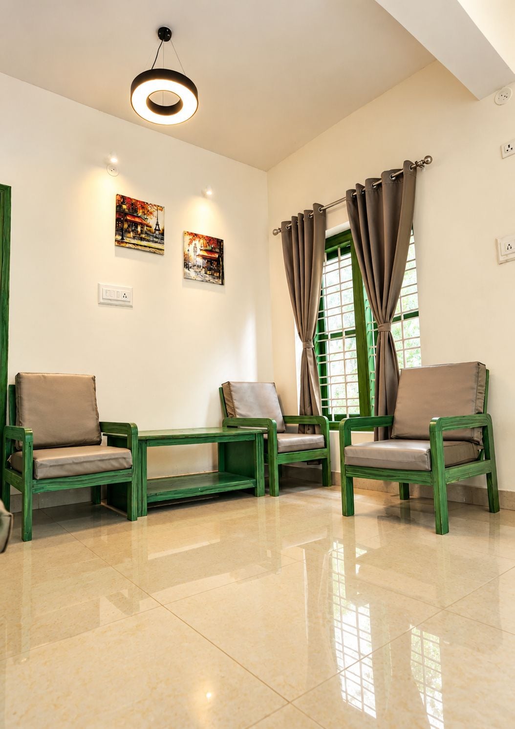 Una habitación con mobiliario verde, una lámpara en el techo y dos cuadros en la pared.