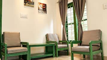 Una habitación con mobiliario verde, una lámpara en el techo y dos cuadros en la pared.