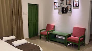 Habitación de hotel con cama, dos sillas, una puerta verde y obras de arte colgadas en la pared.