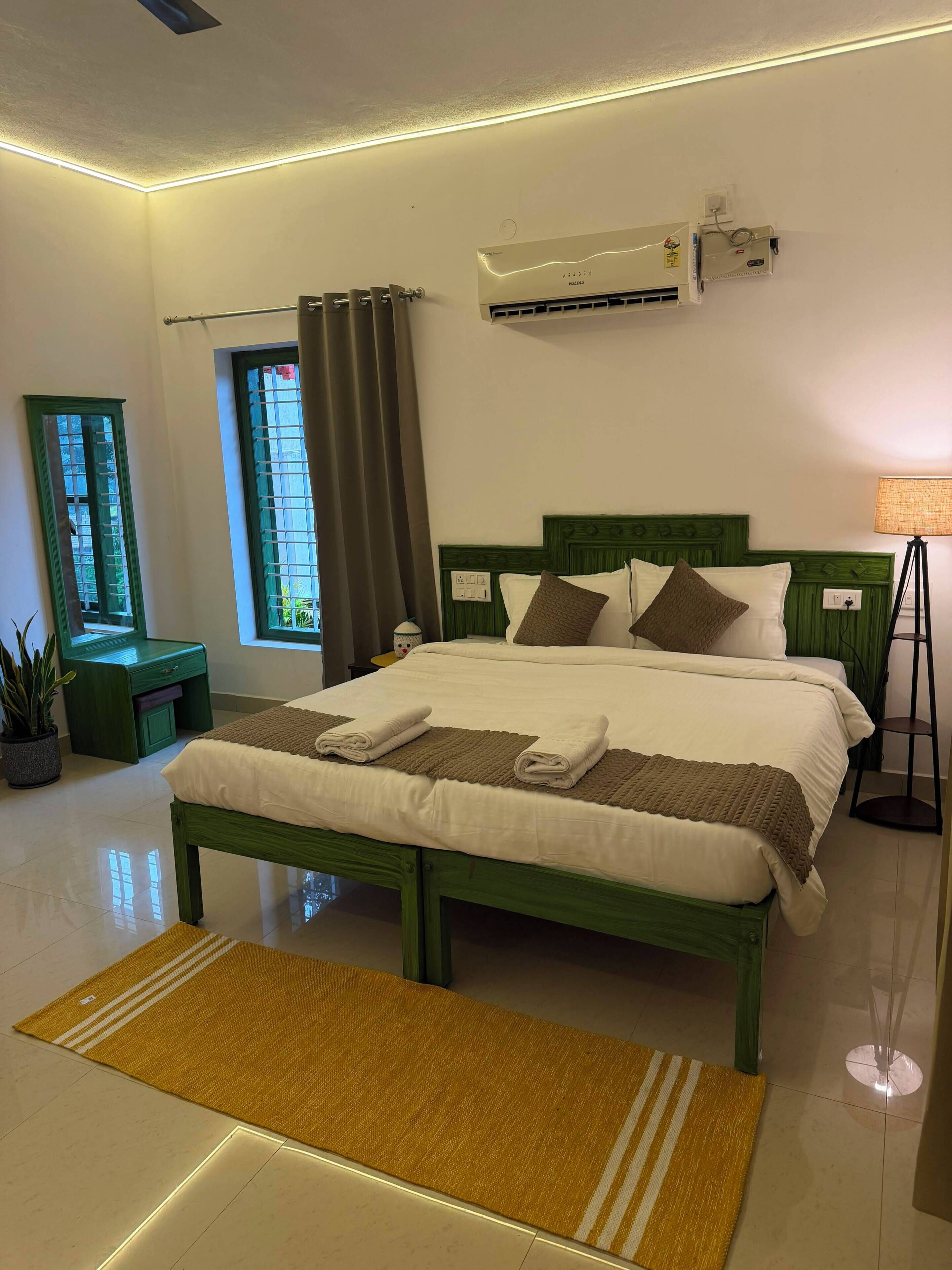 Habitación de hotel con cama, aire acondicionado, lámpara de noche y ventana con cortinas.