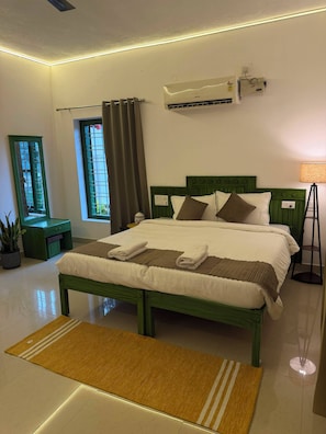 A hotel room with a bed, air conditioning unit, bedside lamp, and a window with curtains. - Hasu Stay (Madikeri)